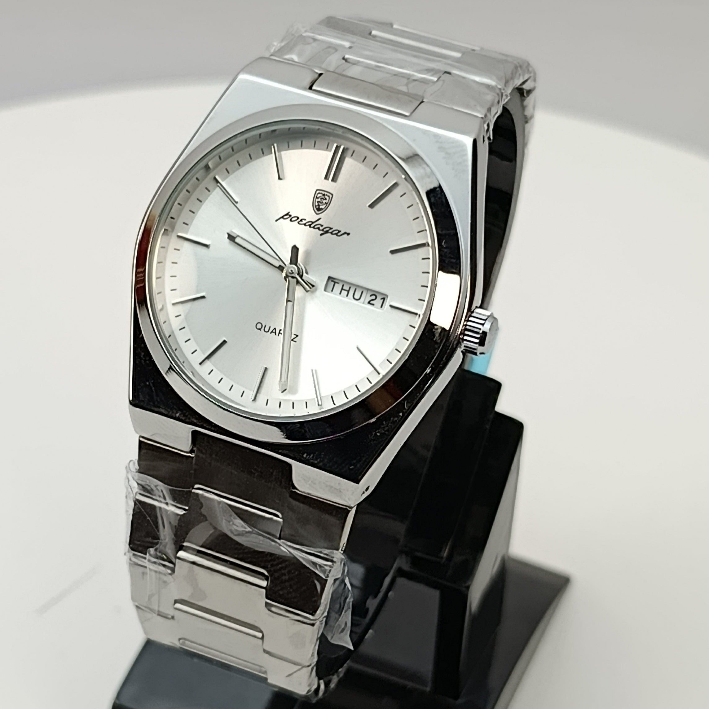 Silver watch on a black stand against a gray background