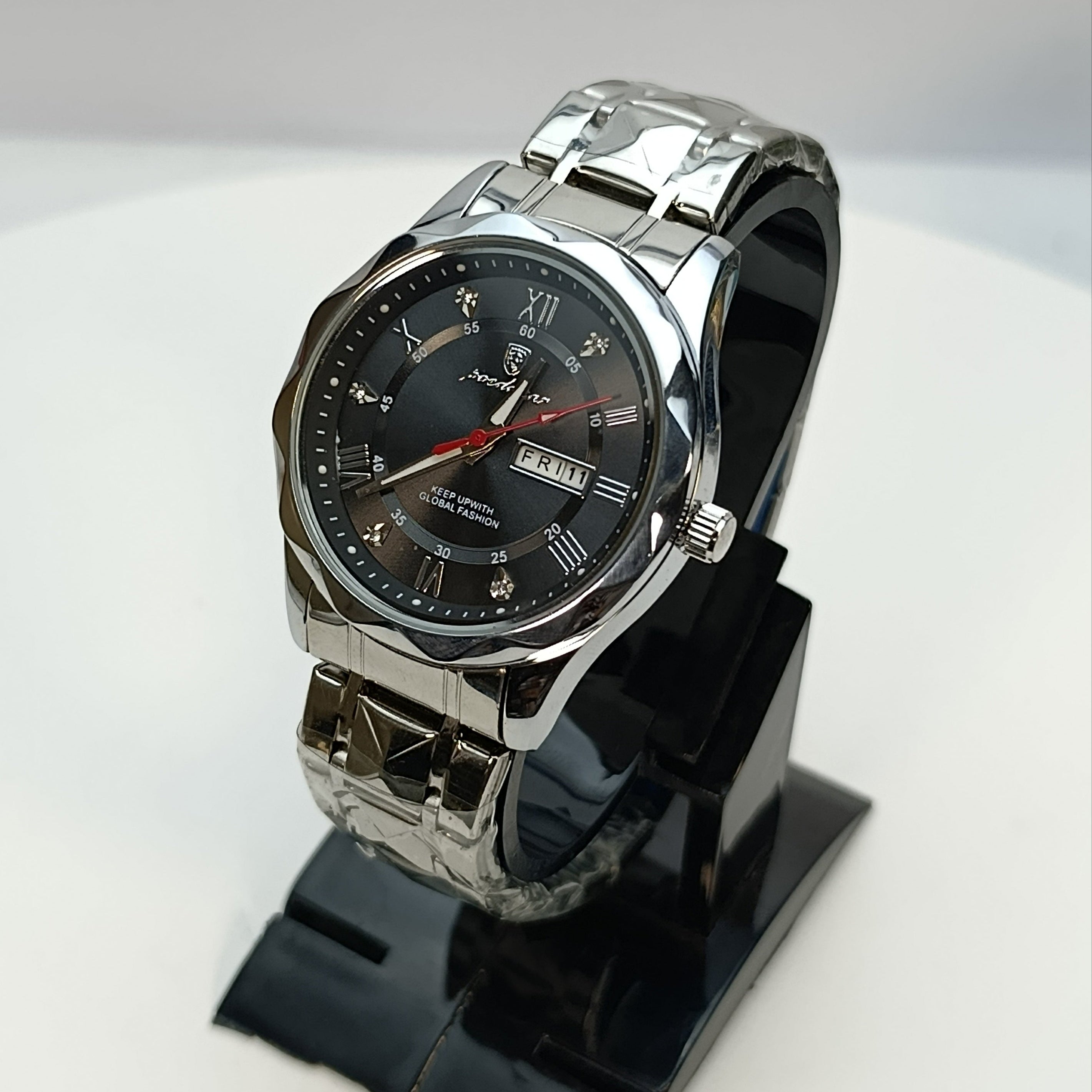 Silver wristwatch on a black stand against a white background