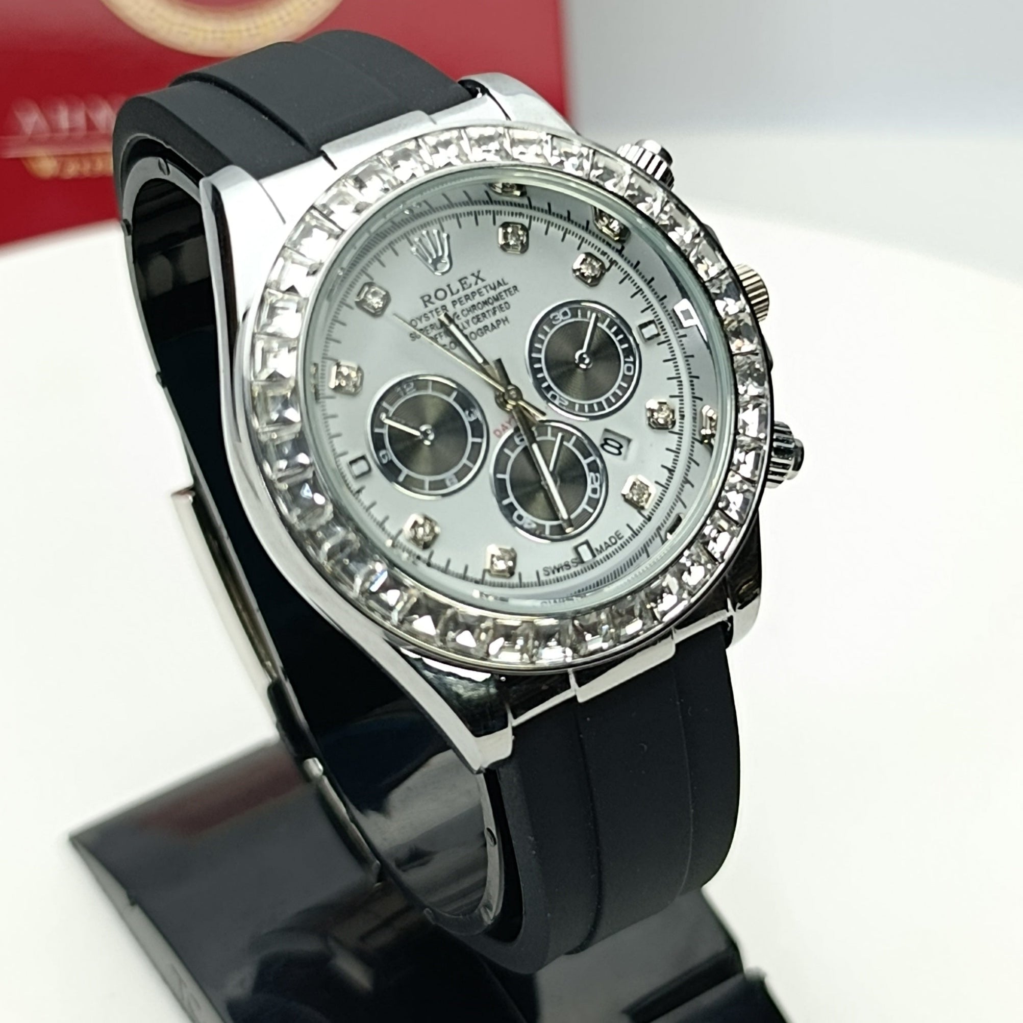 Black wristwatch with silver dial on a stand, brand box in the background