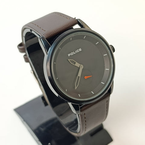 Watch with brown leather strap and dark gray dial on a white background