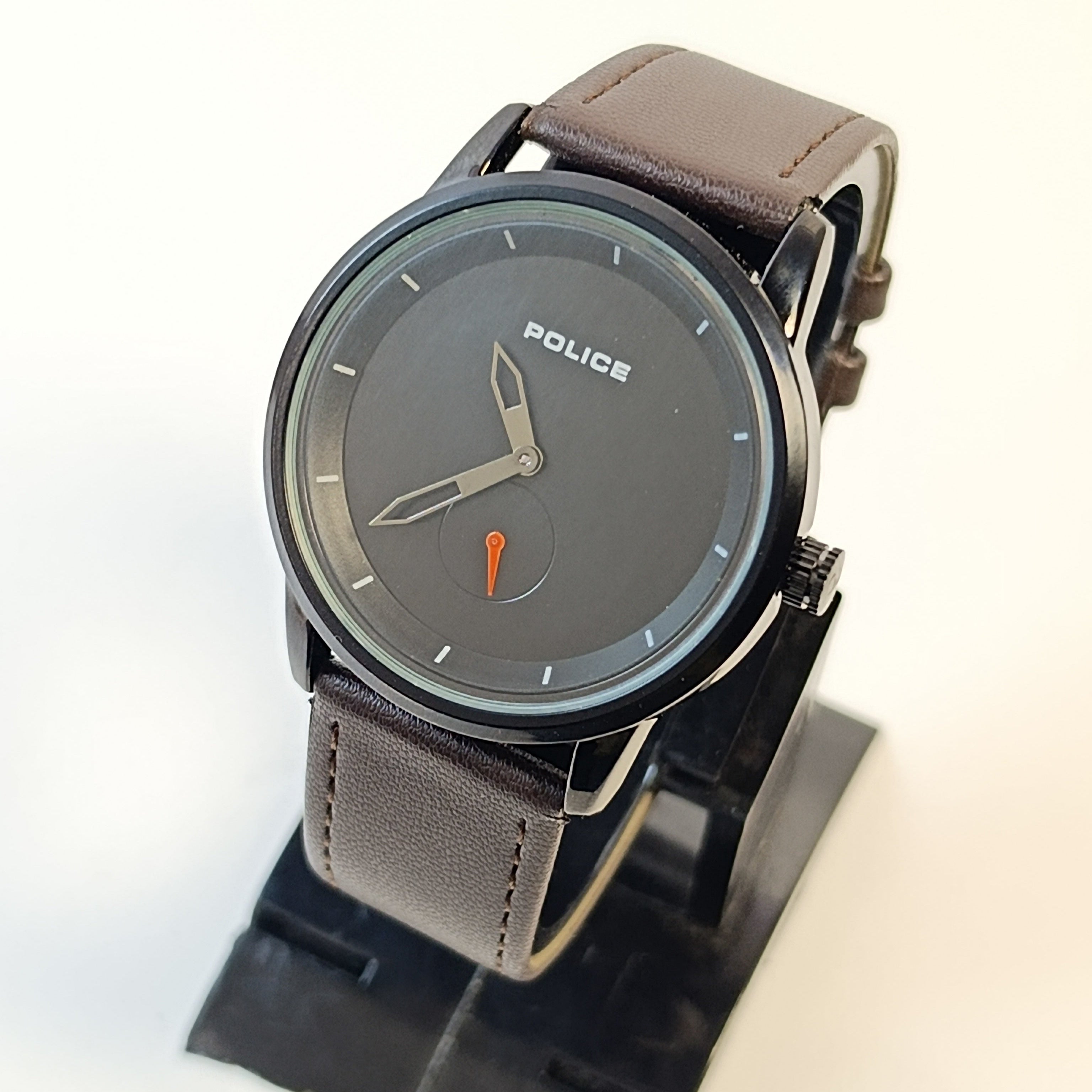 Police watch with brown leather strap on a stand against a white background